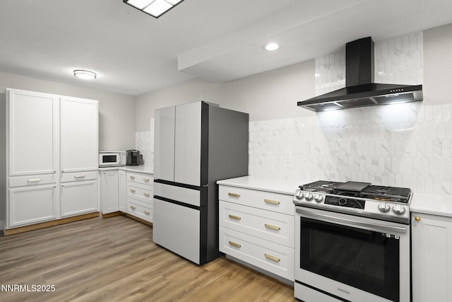 14690 Rancheros Dr, Reno, NV 89521 - kitchen featuring appliances with stainless steel finishes, wall chimney range hood, light countertops, light wood-style floors, and decorative backsplash