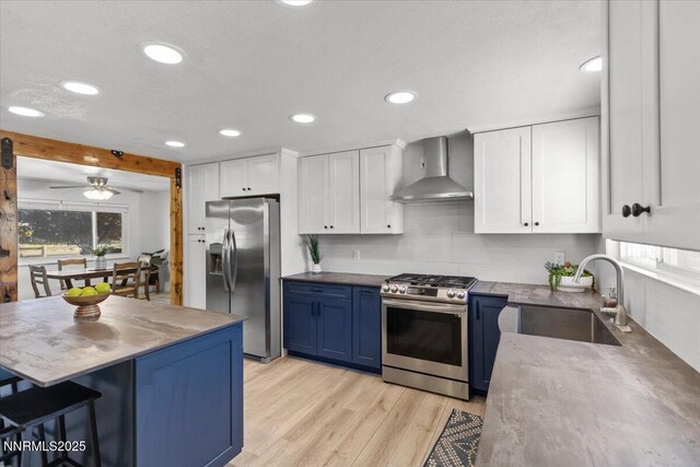 1235 Koontz Ln, Carson City, NV 89701 - kitchen with appliances with stainless steel finishes, wall chimney range hood, a sink, blue cabinetry, and white cabinetry