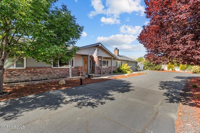 1235 Koontz Ln, Carson City, NV 89701 - view of front of home with brick siding, driveway, an attached garage, and covered porch