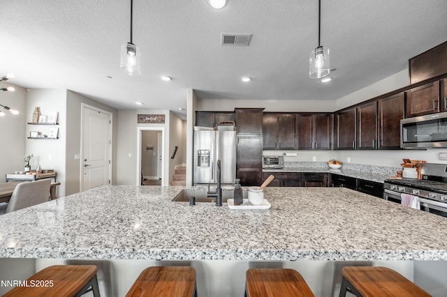 1845 Sea Horse Rd Unit C, Reno, NV 89521 - kitchen featuring stainless steel appliances, dark brown cabinetry, pendant lighting, light stone countertops, and recessed lighting