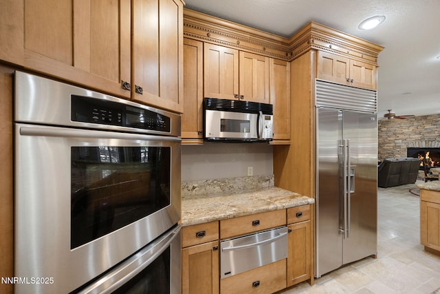 14501 Quail Rock Ct, Reno, NV 89511 - kitchen featuring stainless steel appliances, a warming drawer, a stone fireplace, light stone counters, and open floor plan