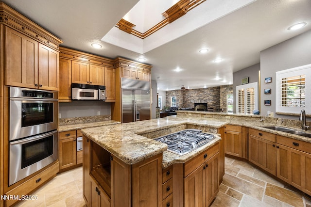 14501 Quail Rock Ct, Reno, NV 89511 - kitchen with stainless steel appliances, a sink, recessed lighting, a stone fireplace, and brown cabinets
