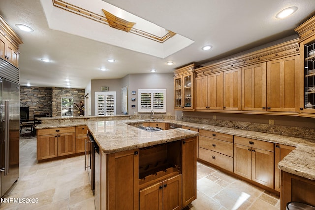 14501 Quail Rock Ct, Reno, NV 89511 - kitchen featuring a skylight, a sink, a fireplace, recessed lighting, and brown cabinetry