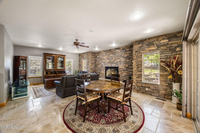 14501 Quail Rock Ct, Reno, NV 89511 - dining space featuring stone tile floors, ceiling fan, recessed lighting, a stone fireplace, and baseboards
