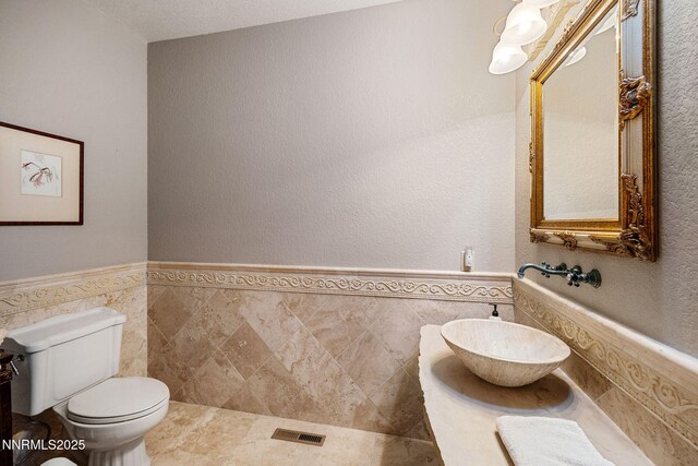 14501 Quail Rock Ct, Reno, NV 89511 - bathroom featuring wainscoting, toilet, tile walls, and vanity
