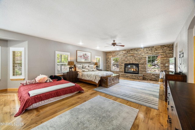 14501 Quail Rock Ct, Reno, NV 89511 - bedroom featuring a stone fireplace, wood-type flooring, baseboards, and a ceiling fan