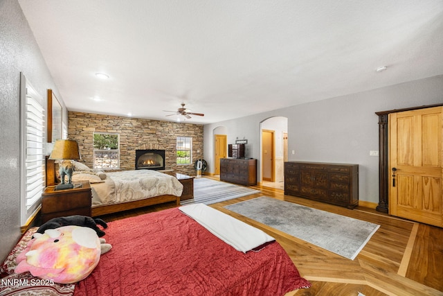14501 Quail Rock Ct, Reno, NV 89511 - bedroom with wood finished floors, arched walkways, a stone fireplace, a ceiling fan, and recessed lighting