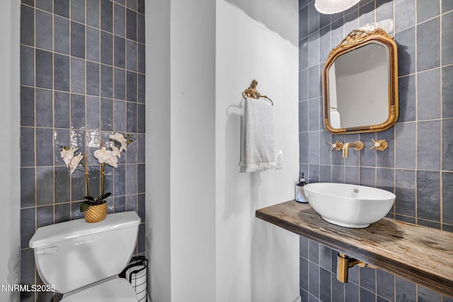 4307 Clyde Ct, Reno, NV 89509 - half bathroom with tile walls, a sink, toilet, and decorative backsplash