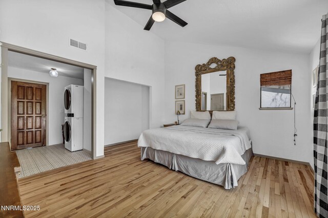 4307 Clyde Ct, Reno, NV 89509 - bedroom featuring stacked washing machine and dryer, light wood-style floors, a ceiling fan, baseboards, and high vaulted ceiling