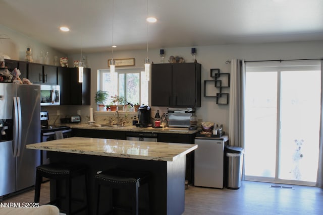1311 Yellowjacket Ln, Gardnerville, NV 89460 - kitchen featuring appliances with stainless steel finishes, a sink, wood finished floors, a kitchen bar, and a kitchen island