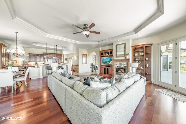 14200 Wild Quail Ct, Reno, NV 89511 - living room with a tray ceiling, a tile fireplace, dark wood-style flooring, ceiling fan, and ornamental molding