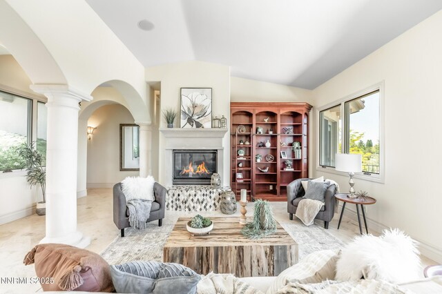 14200 Wild Quail Ct, Reno, NV 89511 - living room featuring arched walkways, decorative columns, a glass covered fireplace, lofted ceiling, and baseboards