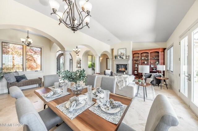 14200 Wild Quail Ct, Reno, NV 89511 - dining room featuring a chandelier, arched walkways, decorative columns, a glass covered fireplace, and vaulted ceiling