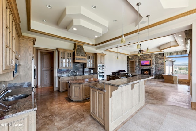 1103 Cortez Ln, Gardnerville, NV 89410 - kitchen featuring a raised ceiling, a sink, a large island, custom range hood, and a stone fireplace