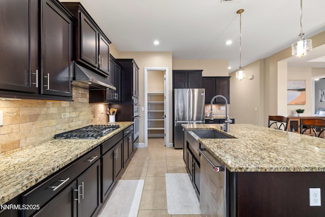 9845 Sea Breeze Ln, Reno, NV 89521 - kitchen featuring under cabinet range hood, stainless steel appliances, a sink, light stone counters, and an island with sink