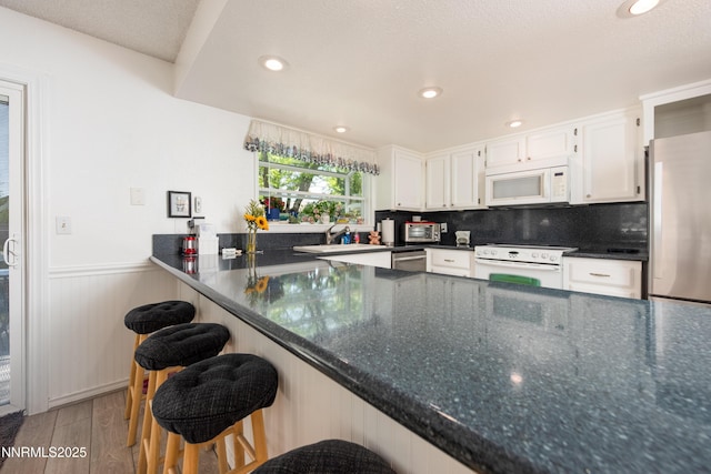 1745 Fir Tree Cir, Minden, NV 89423 - kitchen featuring appliances with stainless steel finishes, wood finished floors, white cabinetry, a wainscoted wall, and a peninsula