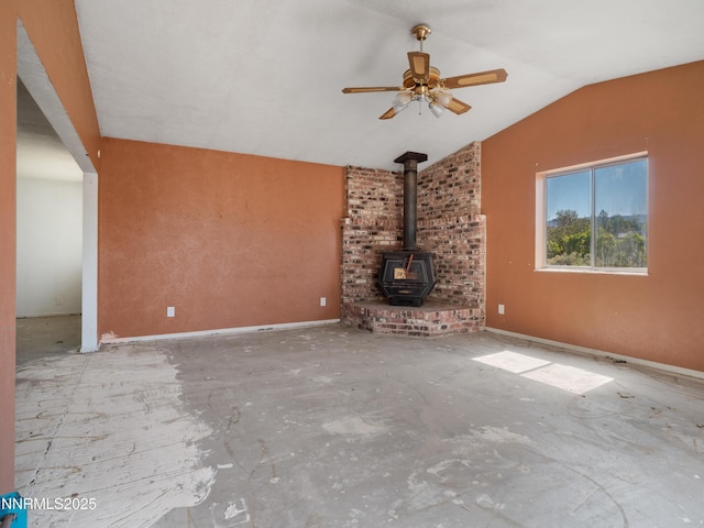 639 Mustang Ln, Gardnerville, NV 89410 - unfurnished living room featuring a wood stove, a ceiling fan, vaulted ceiling, and baseboards