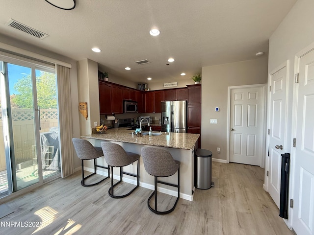 1201 Fonterra Way, Carson City, NV 89701 - kitchen with stainless steel appliances, a peninsula, light wood-style flooring, a breakfast bar area, and baseboards