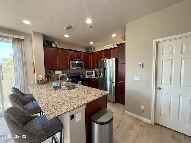 1201 Fonterra Way, Carson City, NV 89701 - kitchen featuring appliances with stainless steel finishes, a sink, a kitchen bar, light wood-style floors, and a peninsula