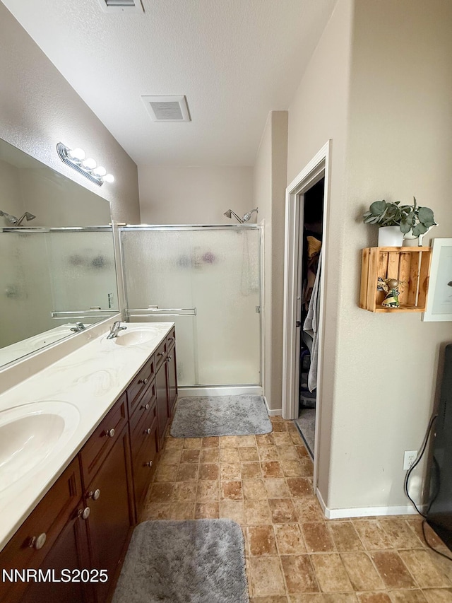 1201 Fonterra Way, Carson City, NV 89701 - bathroom featuring a stall shower, double vanity, a spacious closet, baseboards, and a textured ceiling