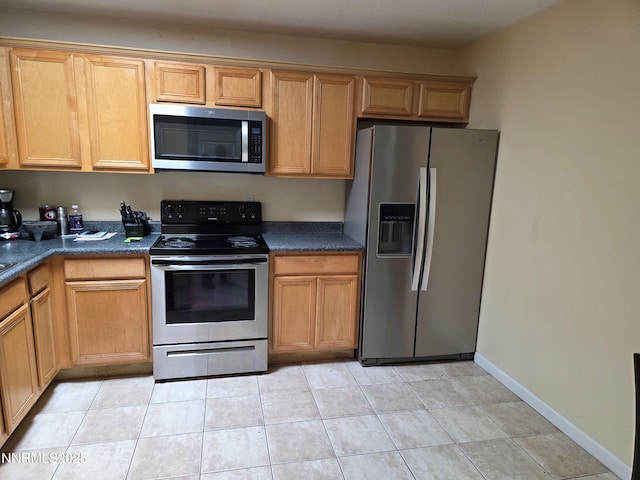 1035 Baywood Dr Unit D, Sparks, NV 89434 - kitchen featuring appliances with stainless steel finishes, dark countertops, light tile patterned floors, and baseboards