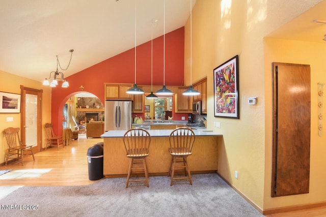 1724 Mohican Dr, South Lake Tahoe, CA 96150 - kitchen with appliances with stainless steel finishes, high vaulted ceiling, a peninsula, light colored carpet, and decorative light fixtures