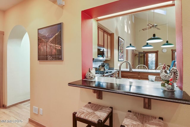 1724 Mohican Dr, South Lake Tahoe, CA 96150 - kitchen featuring stainless steel microwave, a peninsula, dark countertops, a ceiling fan, and wood finished floors