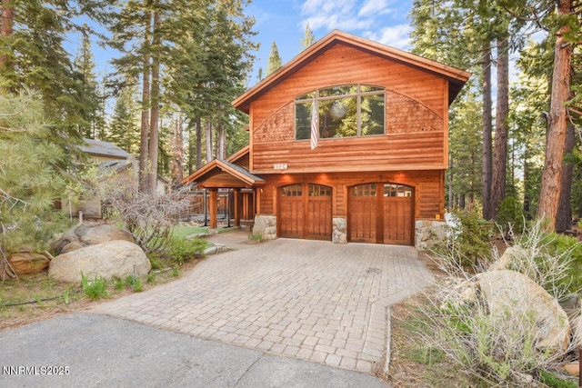 1724 Mohican Dr, South Lake Tahoe, CA 96150 - rustic home featuring an attached garage, stone siding, and decorative driveway
