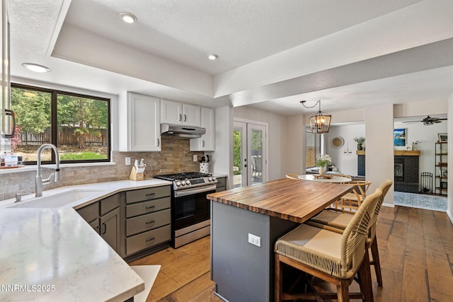 1626 Spring View Ct, Sparks, NV 89436 - kitchen with gas range, under cabinet range hood, a sink, a breakfast bar area, and light wood-type flooring