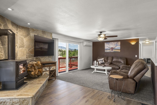 4840 Gentry Ln, Carson City, NV 89701 - living area featuring a wall unit AC, ceiling fan, a wood stove, wood finished floors, and a textured ceiling