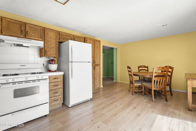 12 S Patterson Pl, Sparks, NV 89436 - kitchen with white appliances, under cabinet range hood, brown cabinets, light wood-style floors, and decorative backsplash