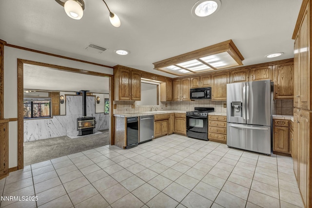 2480 Meadowbrook Ln, Carson City, NV 89701 - kitchen with black appliances, light countertops, a wood stove, brown cabinetry, and light tile patterned flooring