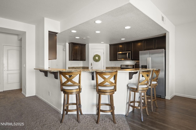 2266 Hayfield Ln, Fernley, NV 89408 - kitchen with appliances with stainless steel finishes, baseboards, recessed lighting, light stone countertops, and a breakfast bar