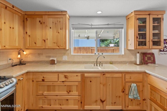 742 Long Valley Rd, Gardnerville, NV 89460 - kitchen with light brown cabinetry, light countertops, stainless steel gas stove, and glass insert cabinets