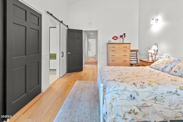 742 Long Valley Rd, Gardnerville, NV 89460 - bedroom featuring a barn door, light wood-style floors, and a towering ceiling