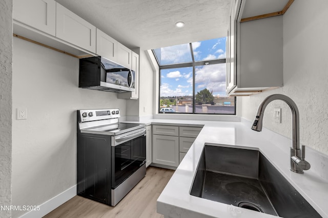 2501 Garfield Ct, Sparks, NV 89431 - kitchen with appliances with stainless steel finishes, a sink, light wood-type flooring, light countertops, and white cabinetry