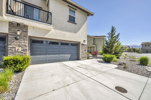1940 Dark Horse Rd Unit C, Reno, NV 89521 - view of front of property featuring a balcony, stone siding, a garage, stucco siding, and concrete driveway