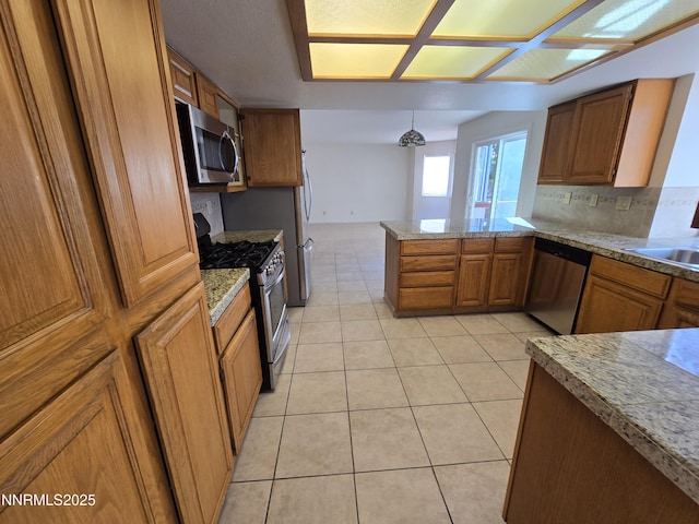 986 Quail Hollow Dr, Reno, NV 89511 - kitchen featuring stainless steel appliances, brown cabinetry, a peninsula, light tile patterned flooring, and decorative backsplash