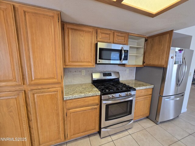 986 Quail Hollow Dr, Reno, NV 89511 - kitchen with appliances with stainless steel finishes, light tile patterned floors, backsplash, and light stone counters