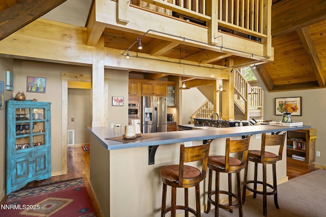 968 Pyrite Ct, Incline Village, NV 89451 - kitchen featuring appliances with stainless steel finishes, wooden ceiling with exposed beams, brown cabinets, baseboards, and a kitchen bar