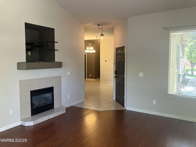 5619 Crescent Hill Way, Sparks, NV 89436 - unfurnished living room with wood finished floors, a tiled fireplace, baseboards, and a chandelier