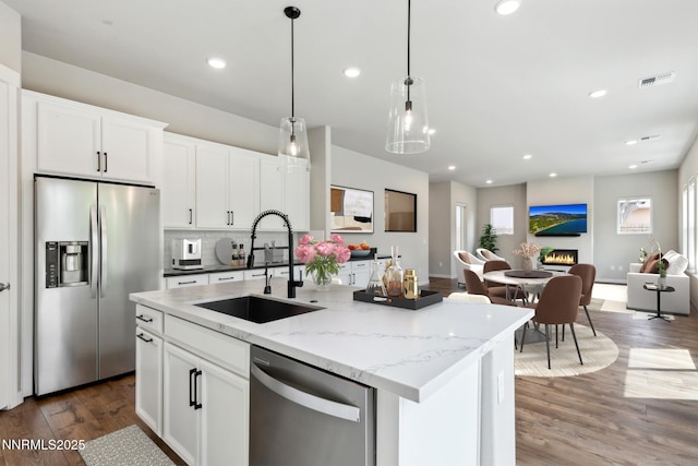 9621 Lane Garrett Dr, Reno, NV 89511 - kitchen with stainless steel appliances, a sink, wood finished floors, open floor plan, and an island with sink