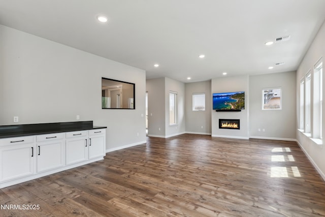 9621 Lane Garrett Dr, Reno, NV 89511 - unfurnished living room with wood finished floors, a glass covered fireplace, baseboards, and recessed lighting
