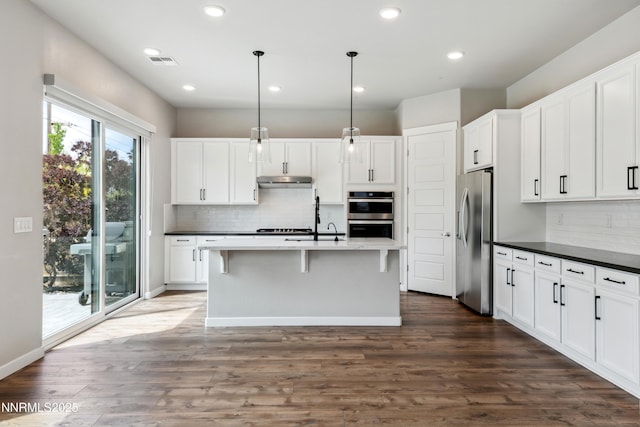 9621 Lane Garrett Dr, Reno, NV 89511 - kitchen featuring appliances with stainless steel finishes, tasteful backsplash, dark countertops, white cabinets, and hanging light fixtures