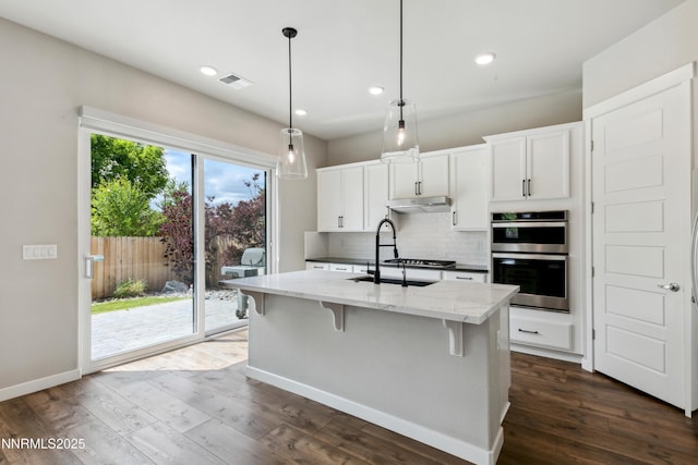 9621 Lane Garrett Dr, Reno, NV 89511 - kitchen featuring a sink, dark wood-type flooring, light stone countertops, double oven, and backsplash