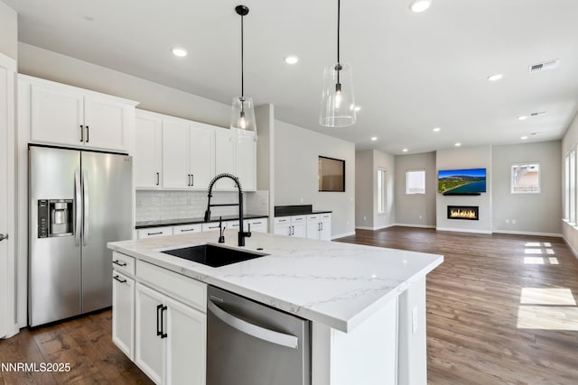 9621 Lane Garrett Dr, Reno, NV 89511 - kitchen featuring appliances with stainless steel finishes, a sink, backsplash, a center island with sink, and wood finished floors