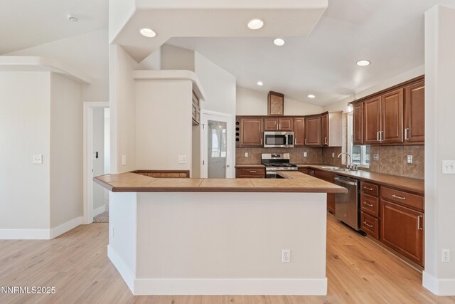 1260 Badger St, Silver Springs, NV 89429 - kitchen featuring stainless steel appliances, a sink, vaulted ceiling, light wood-style flooring, and backsplash