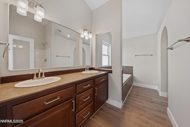1260 Badger St, Silver Springs, NV 89429 - bathroom featuring a garden tub, double vanity, wood finished floors, a shower, and baseboards