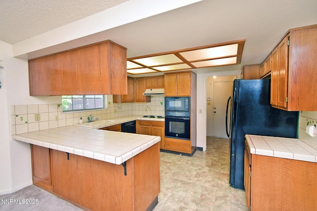 1664 Shadow Wood Rd, Reno, NV 89523 - kitchen with black appliances, under cabinet range hood, a peninsula, and decorative backsplash