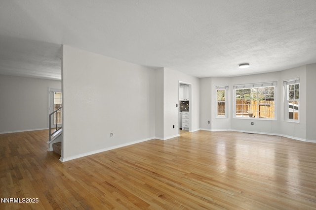 2125 Woodhaven Ln, Sparks, NV 89434 - unfurnished living room with light wood-type flooring, baseboards, stairway, and a textured ceiling